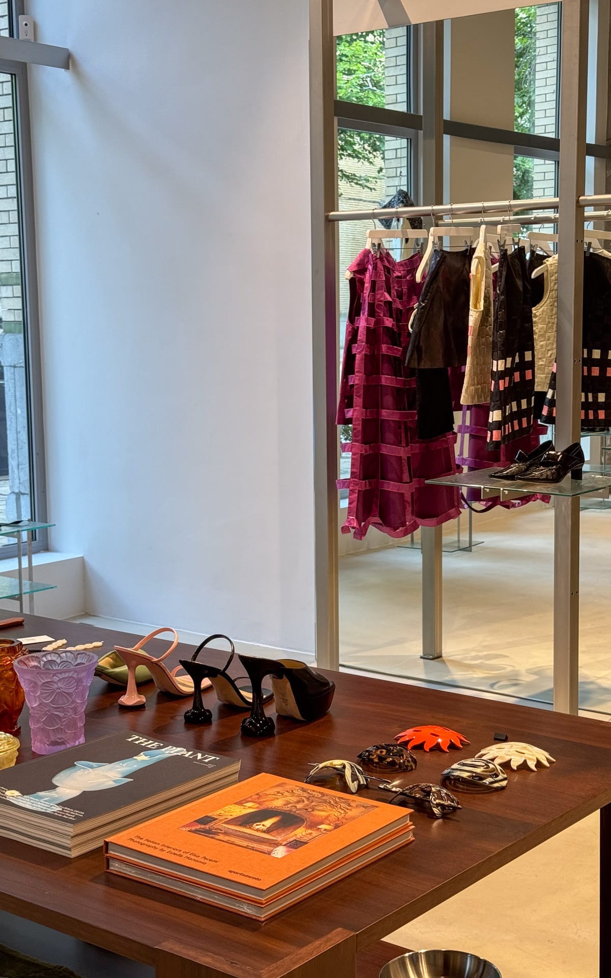The boutique interior of The Menu, Antwerp with fashion books, heels, accessories, and bold designer pieces hanging.