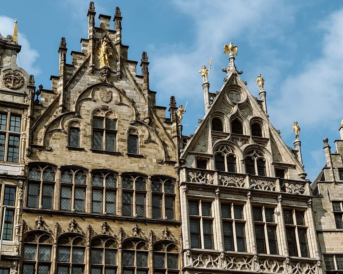 Ornate façades of historic guildhalls in Antwerp’s Grote Markt, adorned with gold statues and intricate stonework.