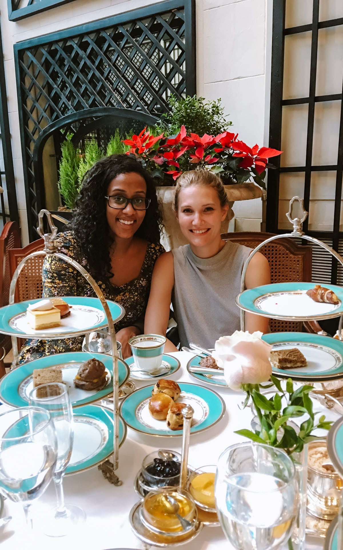 Cec and her friend smiling over afternoon tea at L'Orangerie in Recoleta, with tiered trays of pastries, scones, and delicate china plates.