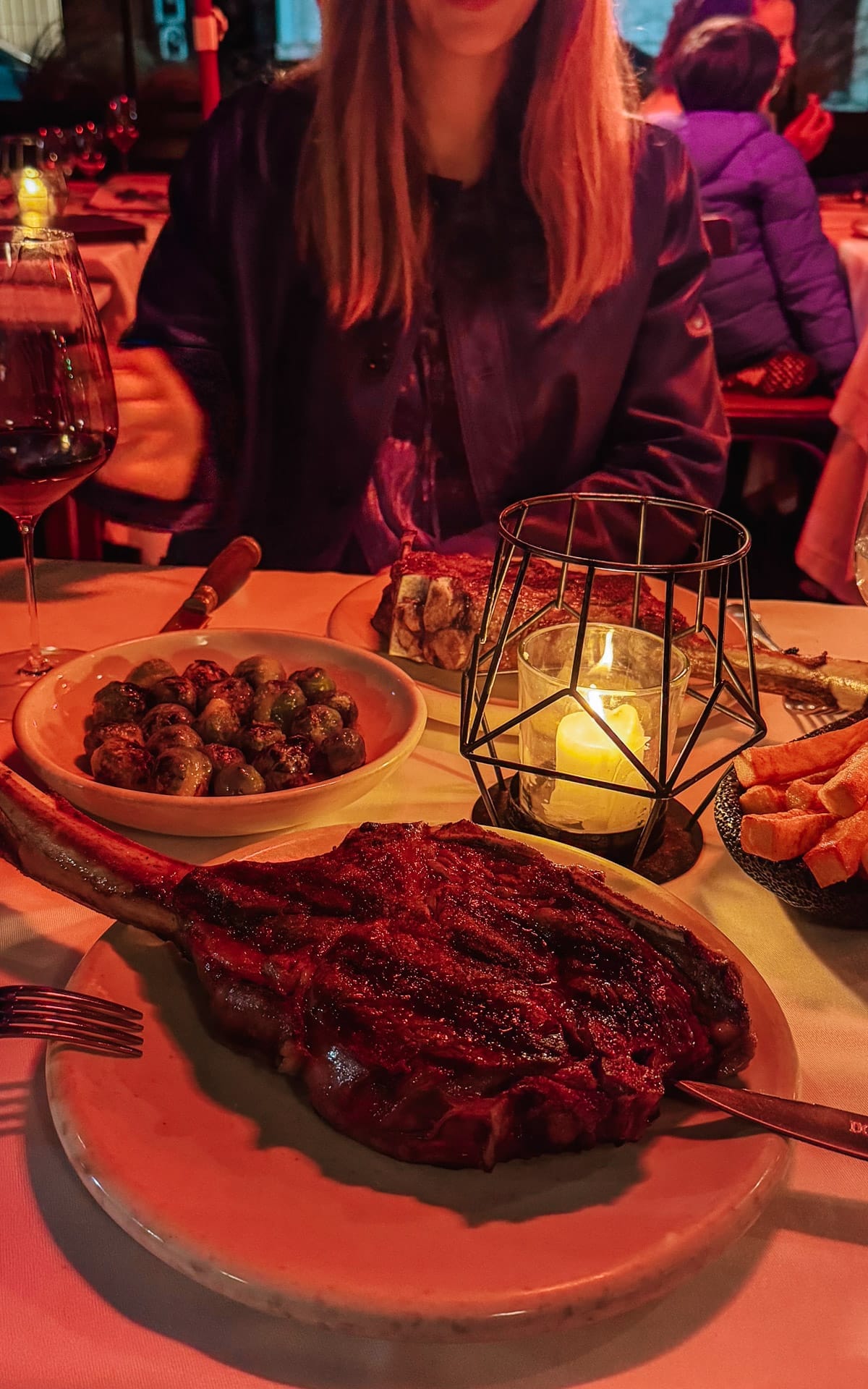 Grilled tomahawk steak with sides of brussels sprouts and fries, served by candlelight at Don Julio.