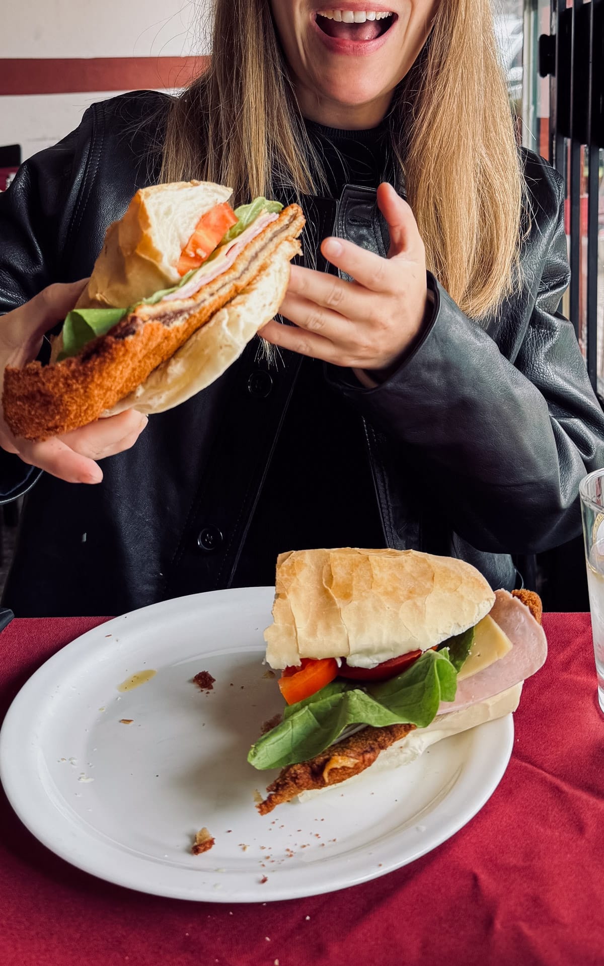 Cec holding a giant milanesa sandwich with ham, cheese, lettuce, and tomato from Los Dos Hermanos in Buenos Aires.