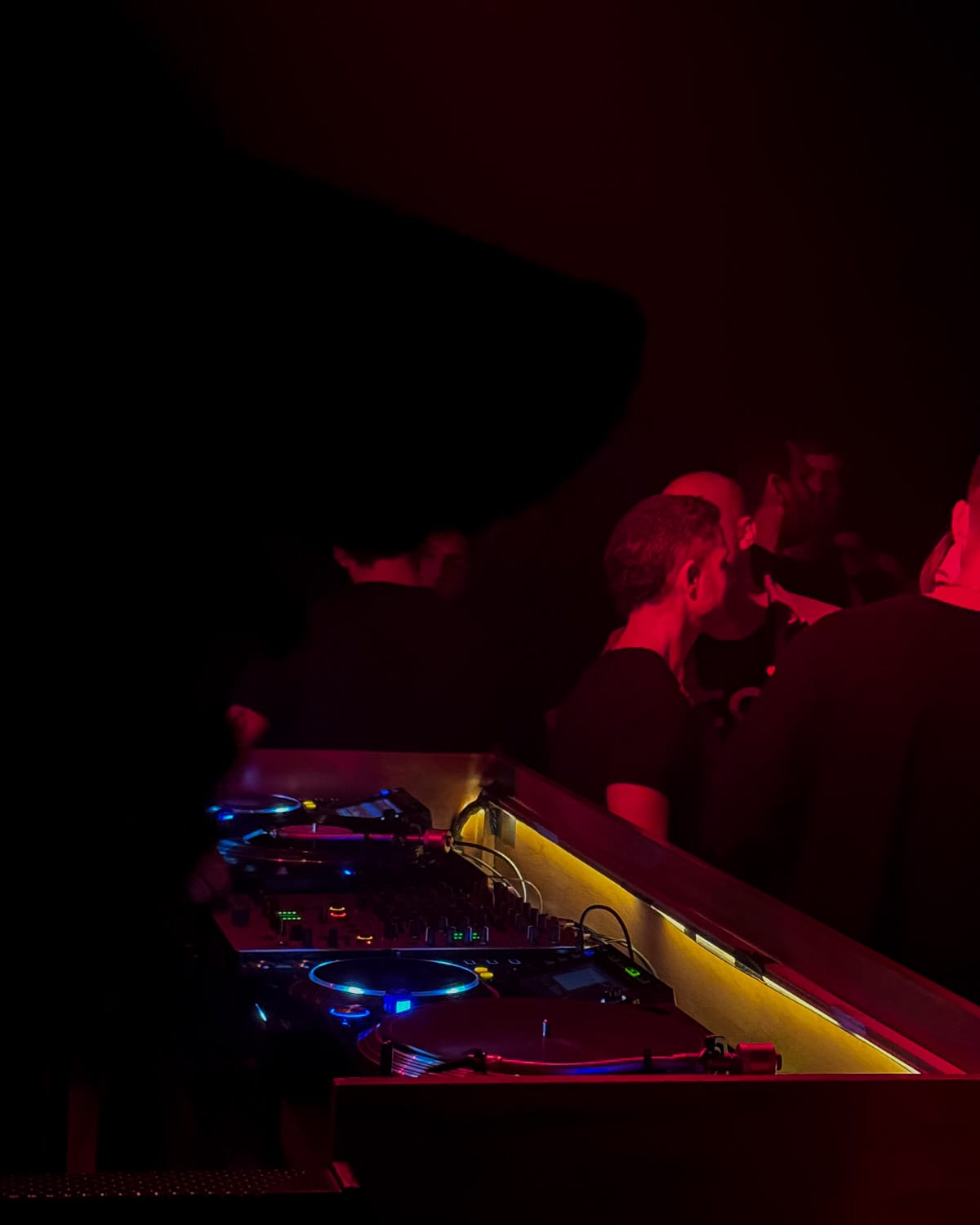Nightclub scene with glowing DJ turntables and a crowd in red lighting at Artlab in Buenos Aires.