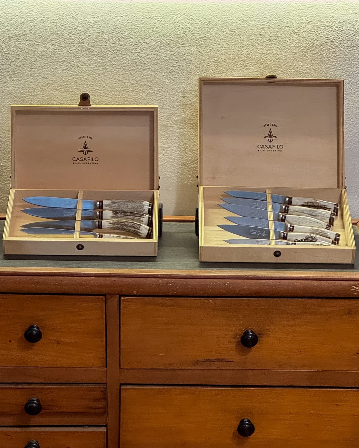 Display of two wooden boxes filled with handcrafted knives with horn handles at Casa Filo in Buenos Aires.
