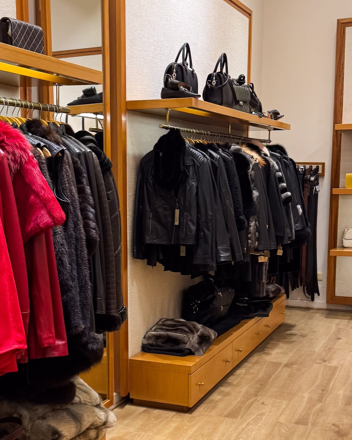 Rossi & Caruso boutique in Recoleta lined with racks of fur and leather jackets, handbags displayed neatly on wooden shelves.