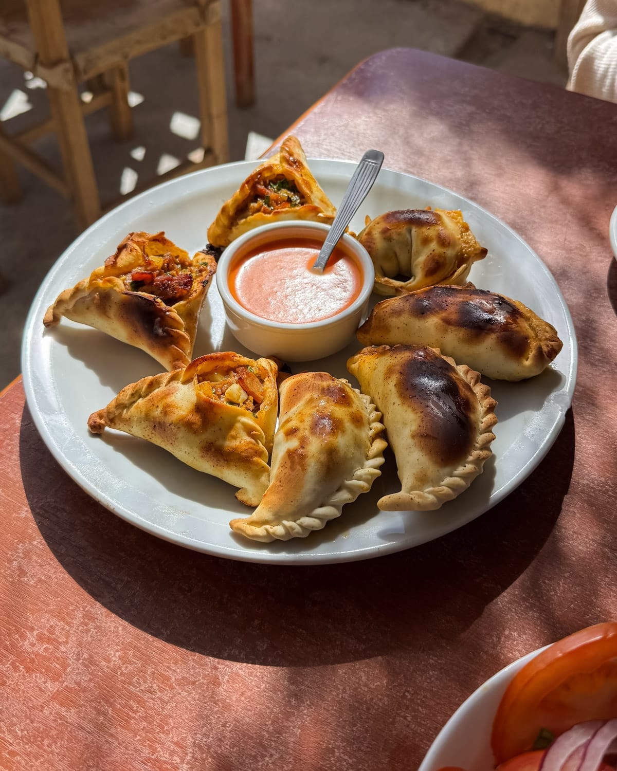 Plate of freshly baked empanadas with red dipping sauce served at a Mi Favorita Cachi.