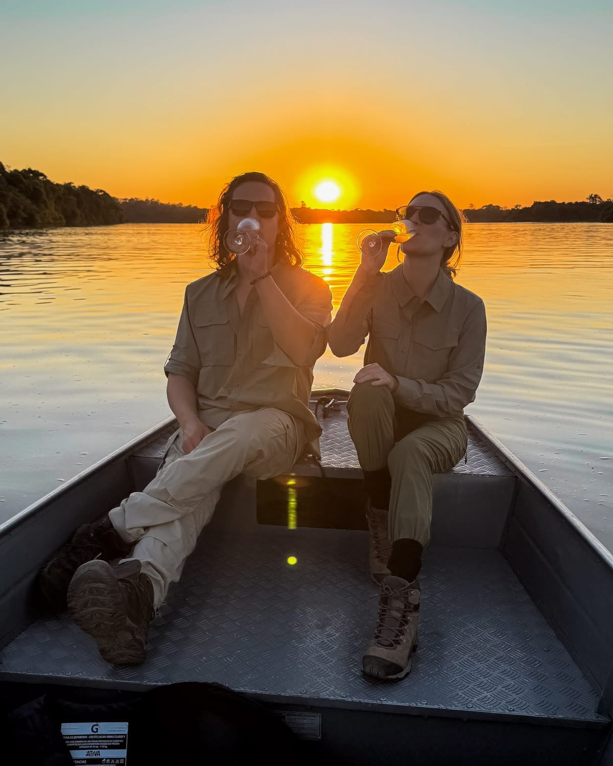 Cec and Ari drinking champagne on a small boat during sunset on the Amazon River.
