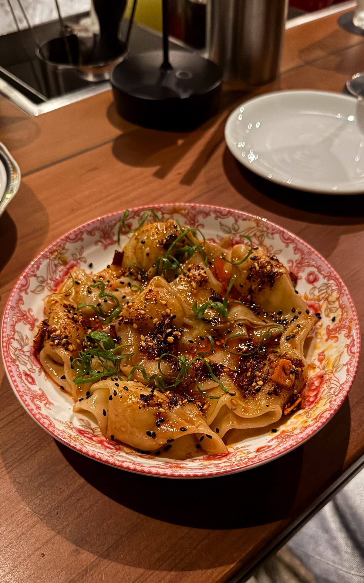 Spicy chili oil dumplings served in a patterned bowl at Tan Tan in São Paulo.