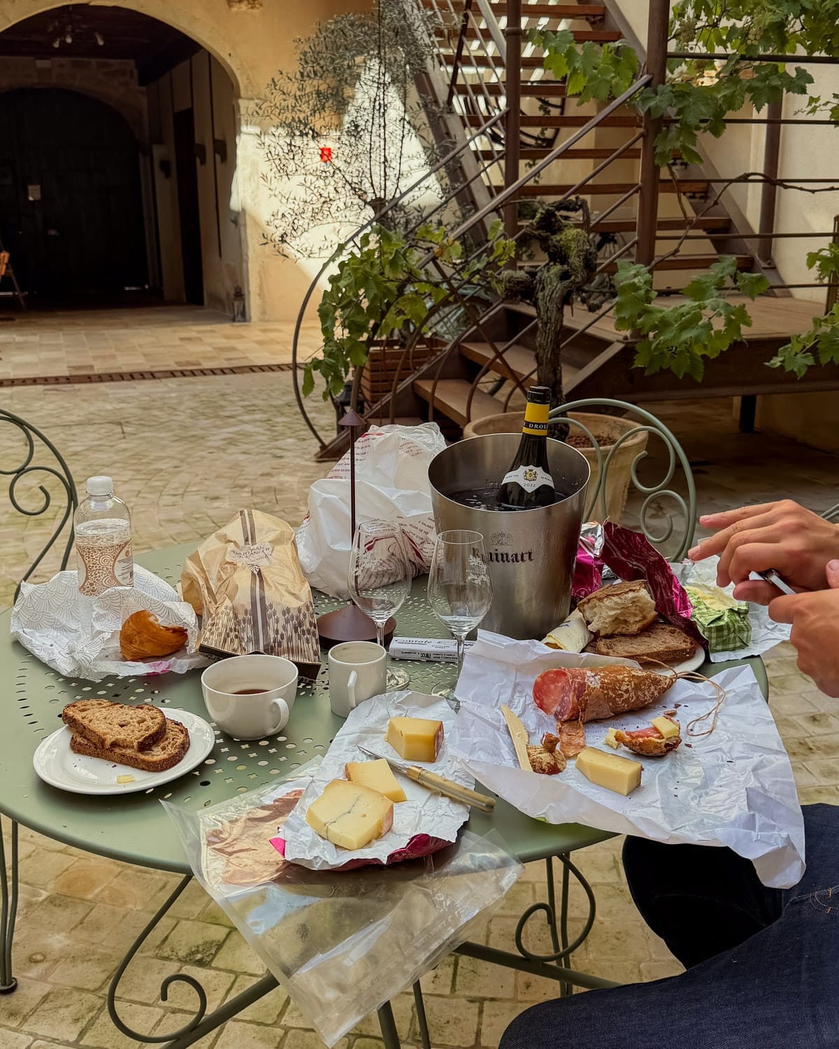 Wine picnic in the courtyard of Le Clos Sainte Marguerite in Beaune with Comté, charcuterie, fresh bread, and Burgundy wine.