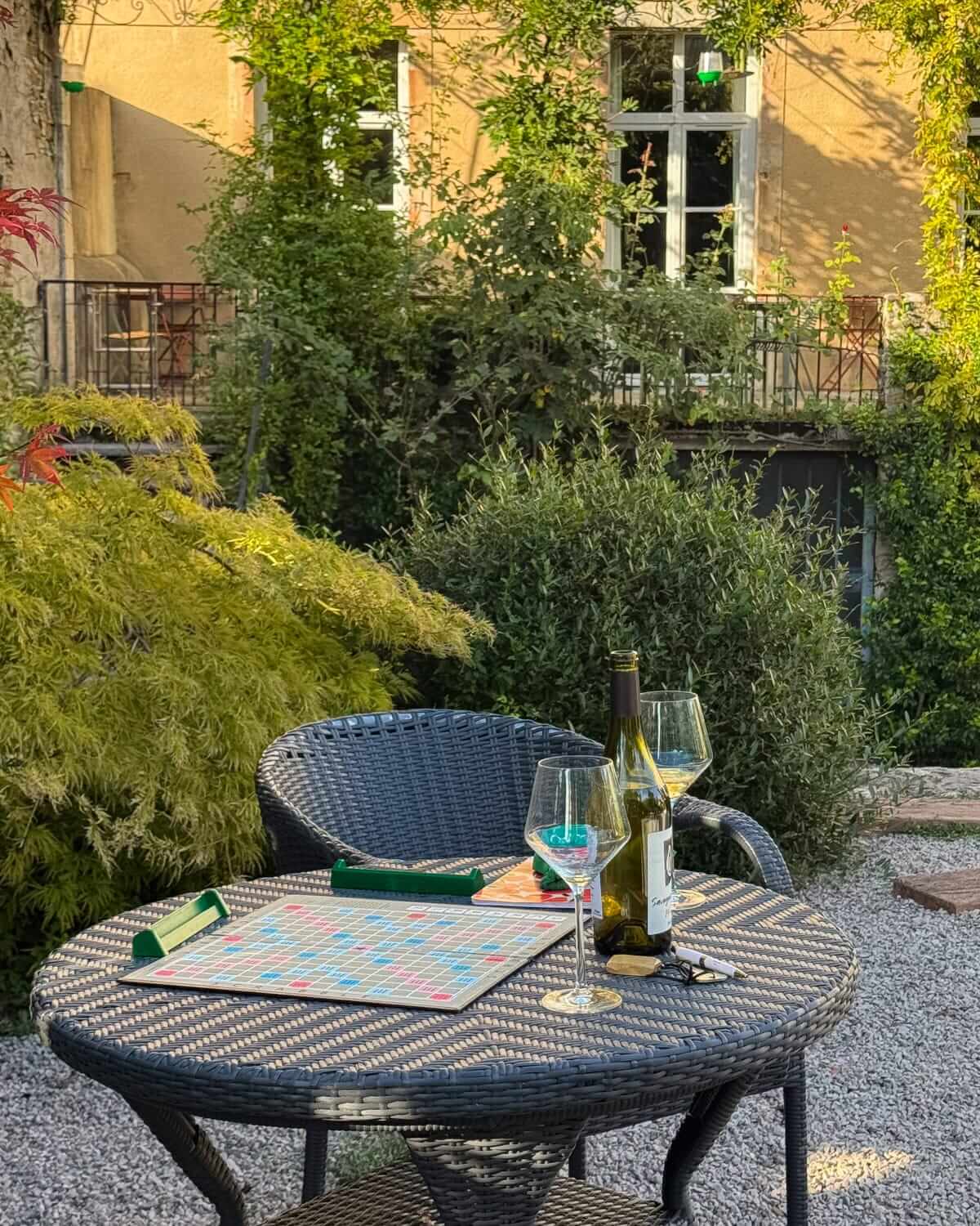 Wine glasses and Scrabble board set in the garden at La Closerie des Capucines in Arbois.