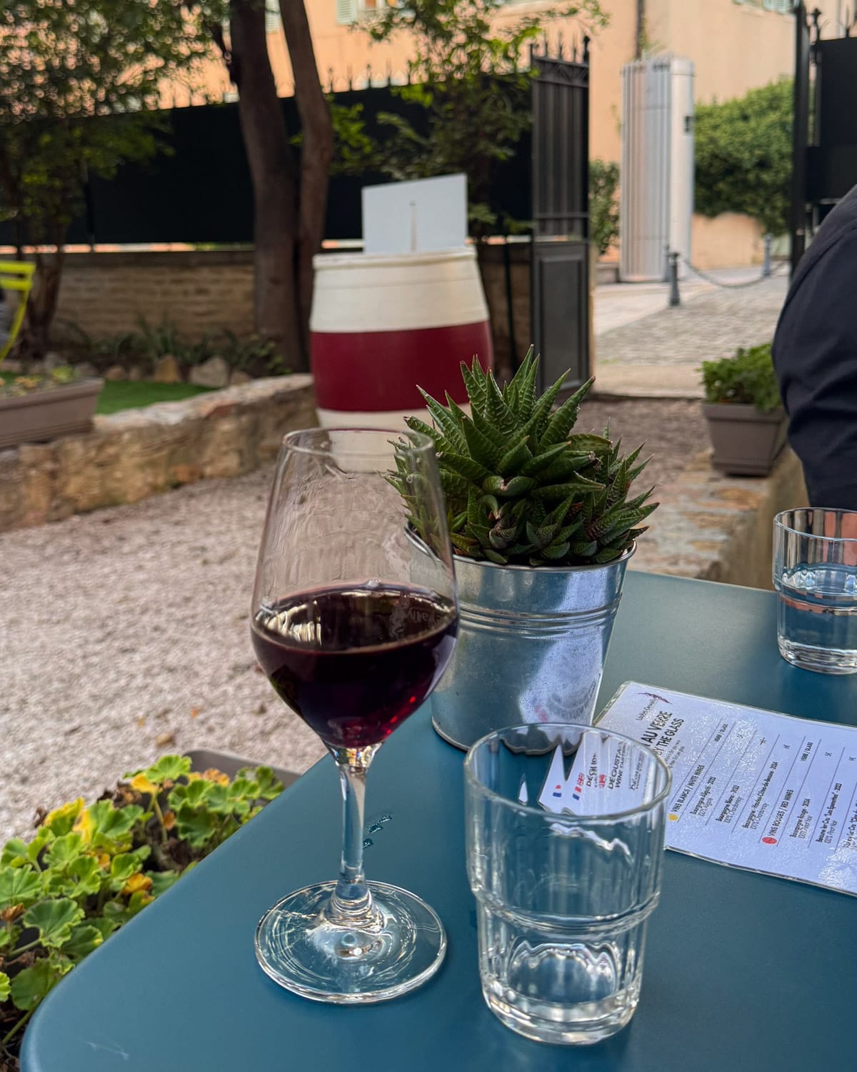 Glass of red Burgundy wine on a courtyard table at Caveau de Dégustation Vins de Bourgogne du Domaine Loubet-Dewailly.