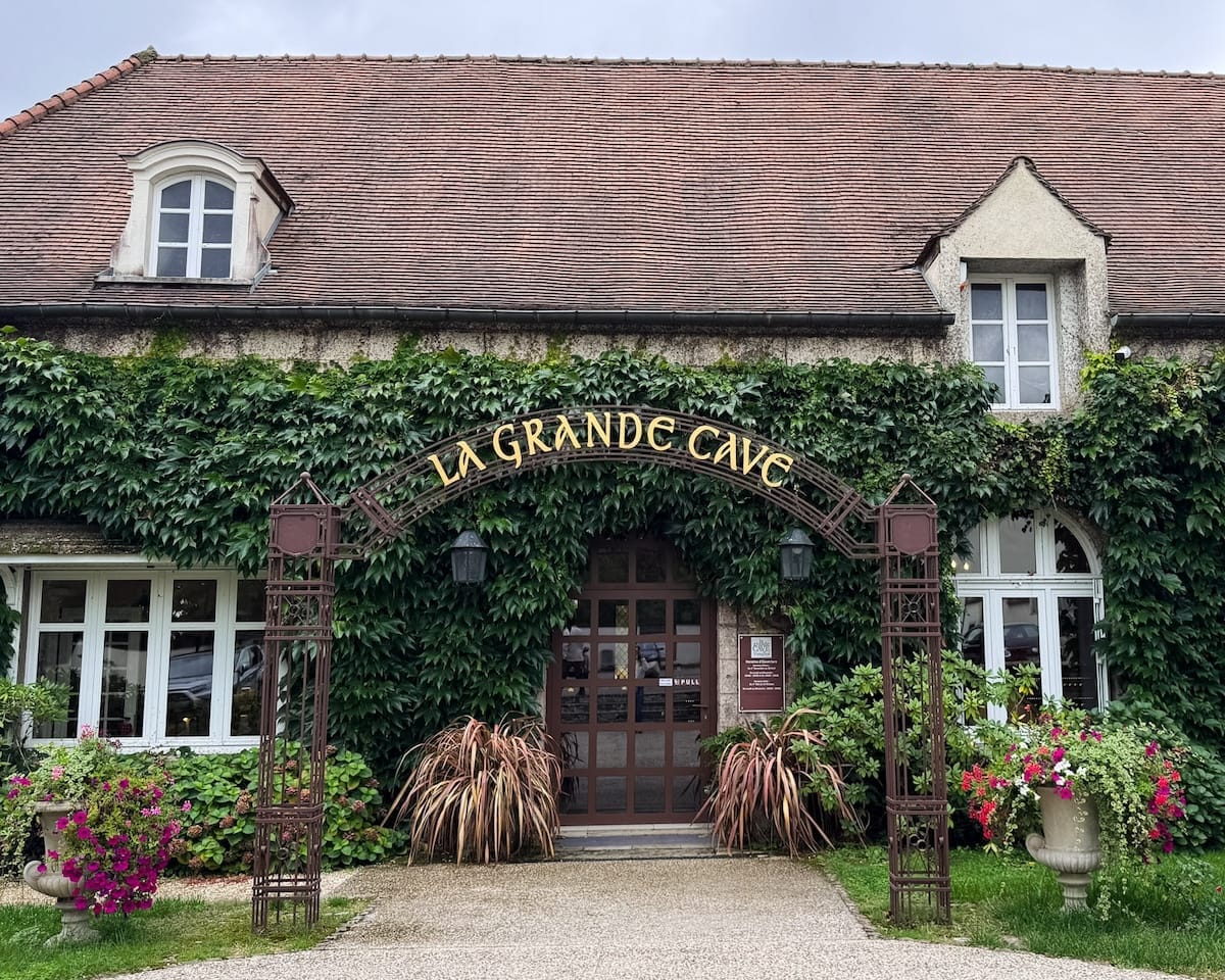 Entrance to La Grande Cave de Vougeot in Beaune with ivy-covered stone exterior.