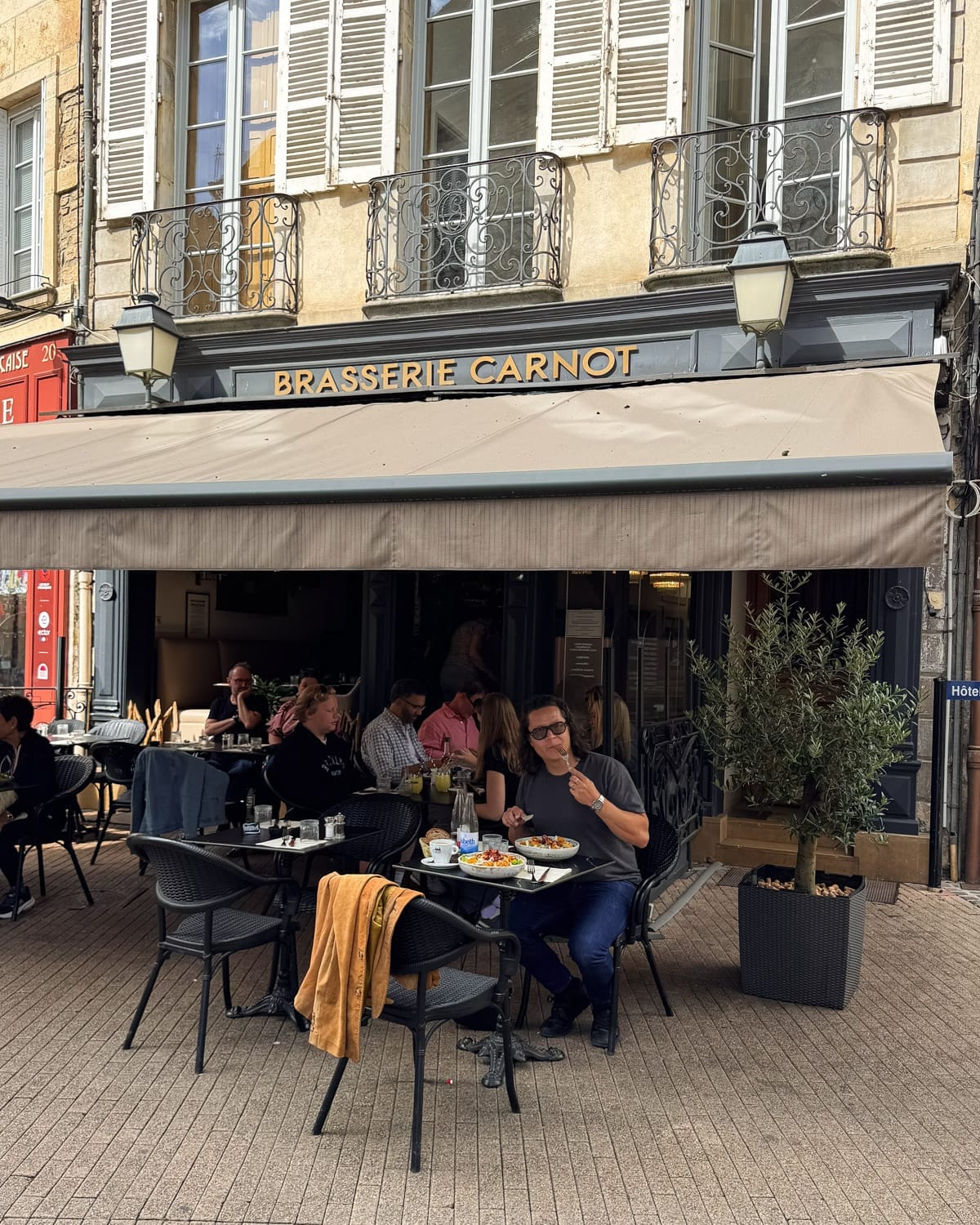 Ari dining at an outdoor table for lunch at Brasserie Carnot in Beaune's historic centre.