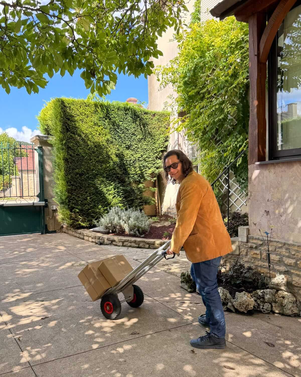 Ari moving boxed wine bottles to his car on a hand truck at a winery in Burgundy.