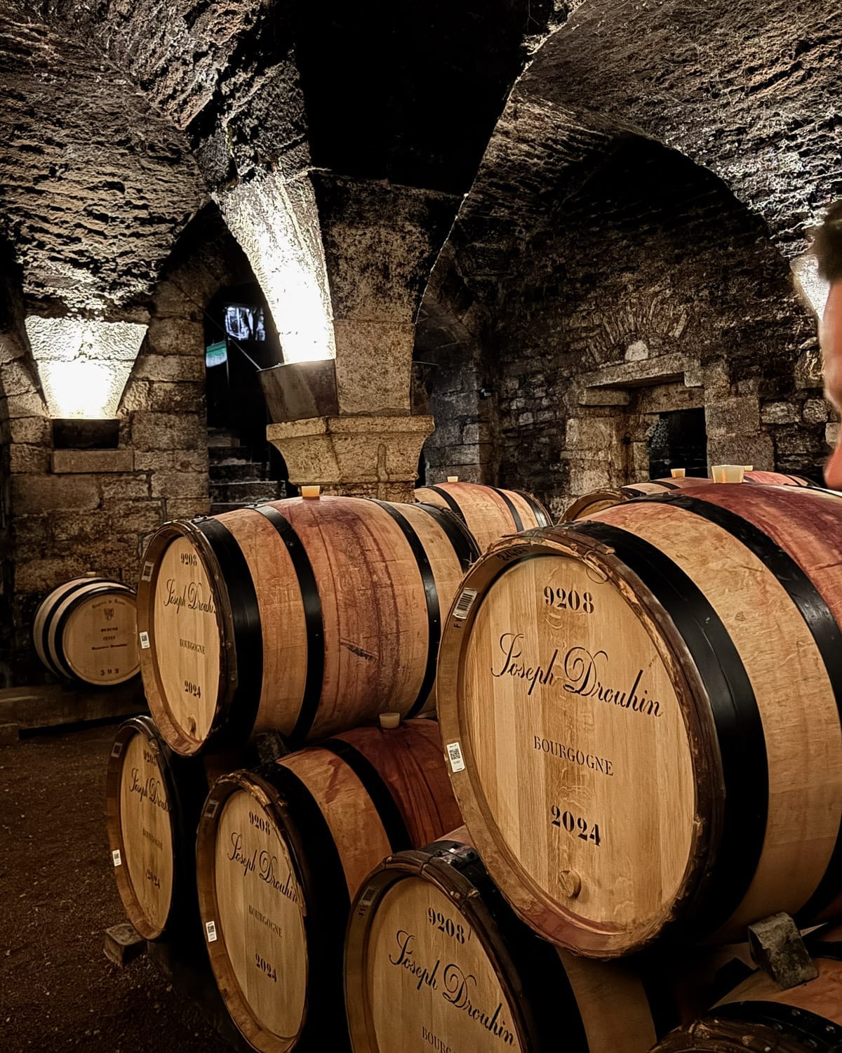 Oak barrels labelled Joseph Drouhin stacked inside the stone cellar at Maison Joseph Drouhin in Beaune.