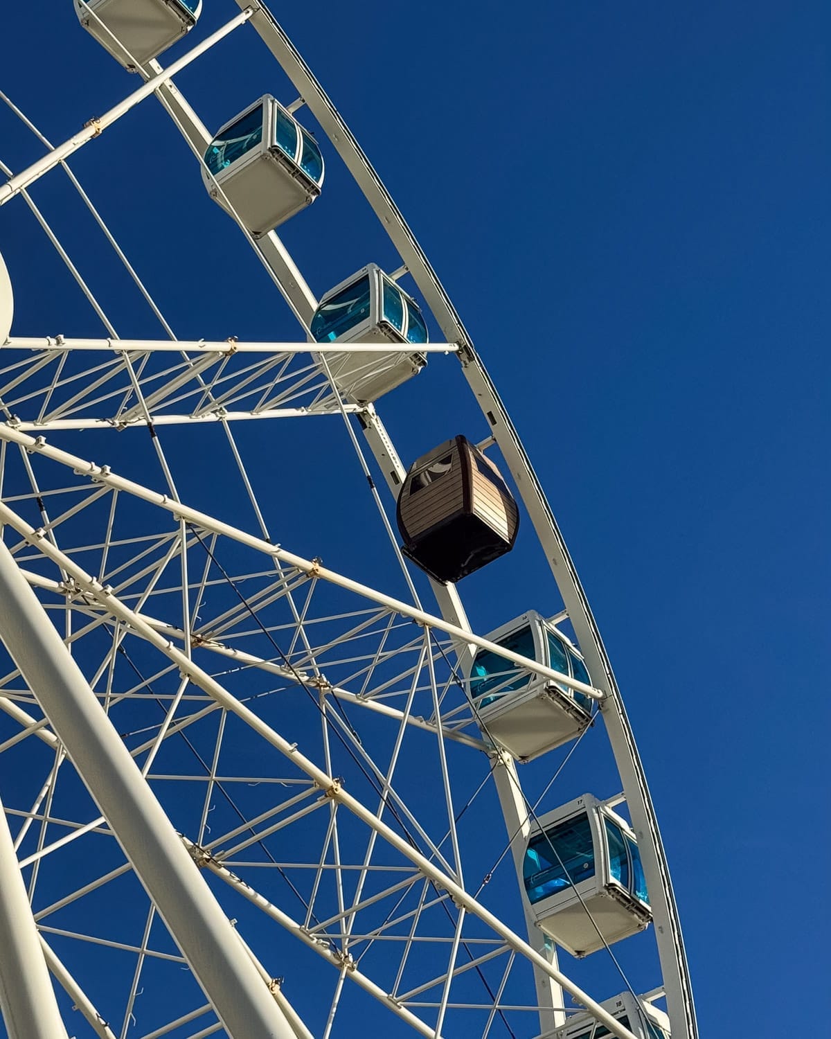 SkyWheel Helsinki ferris wheel cabins against a clear blue sky, including the sauna cabin.