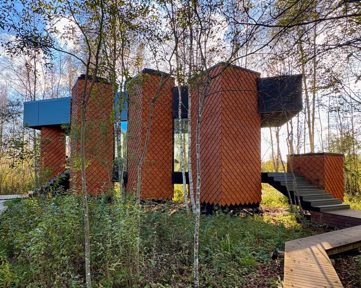 Contemporary wood-clad Kabi villa with geometric terraces elevated above the forest floor at Maidla Natrure Resort.