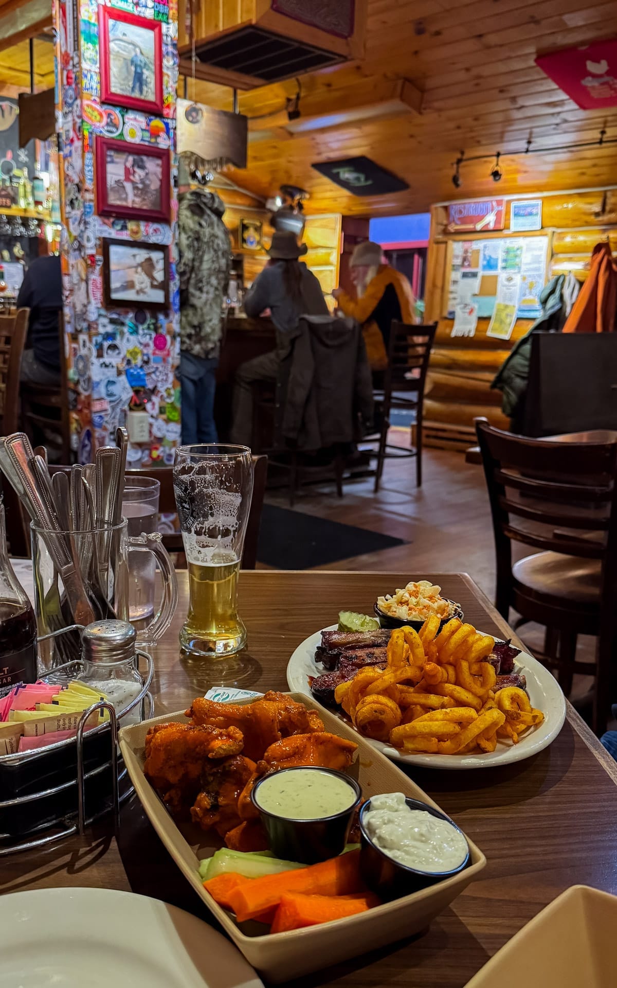 BBQ ribs, curly fries, and buffalo wings with beer inside a rustic log cabin brewpub in Talkeetna.