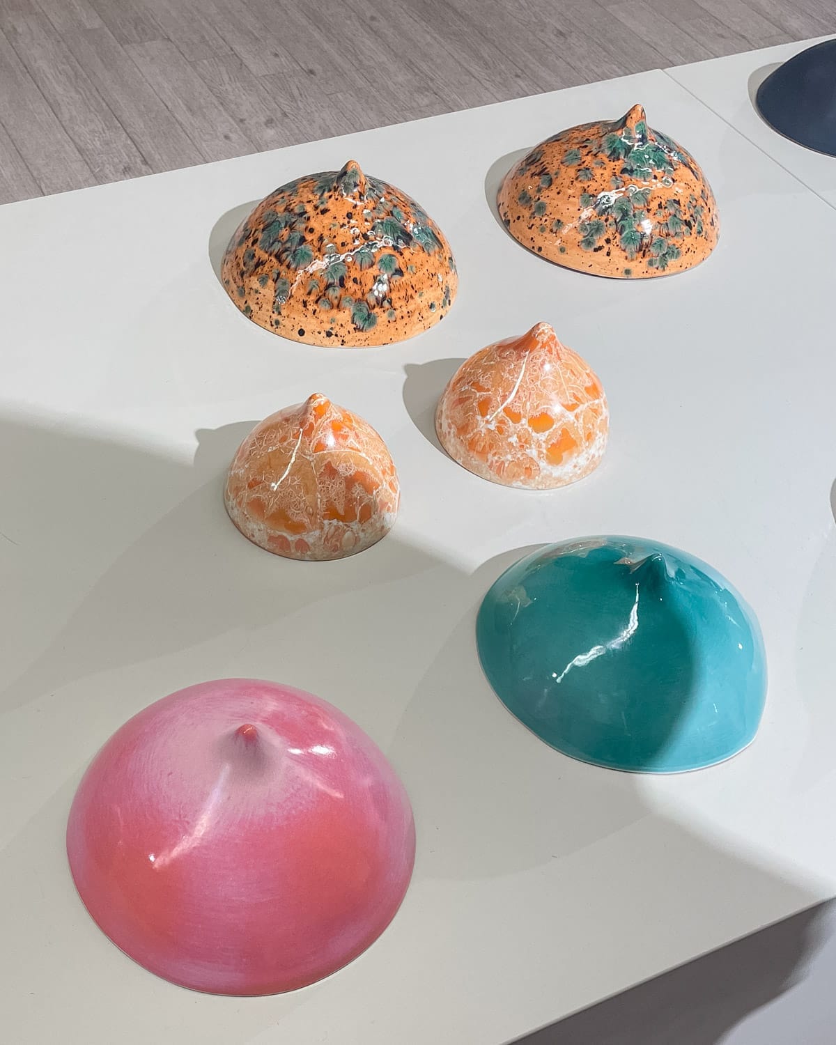 Colourful glossy ceramic boob sculptures at an exhibition for sale.