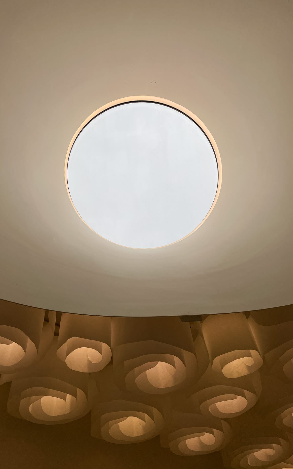 Circular skylight at Amos Rex in Helsinki, with sculptural layered ceiling details surrounding the opening.