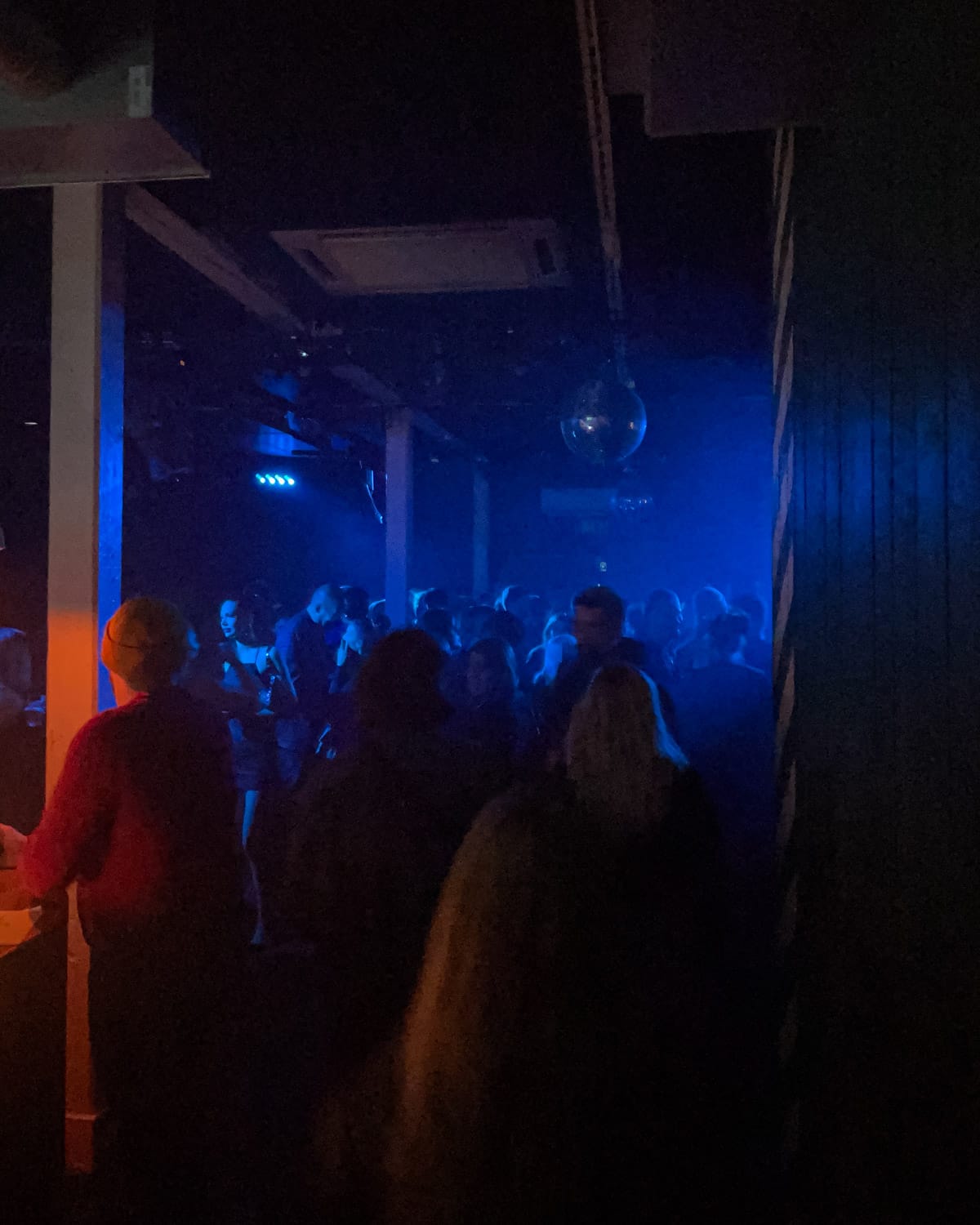 Peopel dancing at Kaiku nightclub in Helsinki with blue lighting and a disco ball.