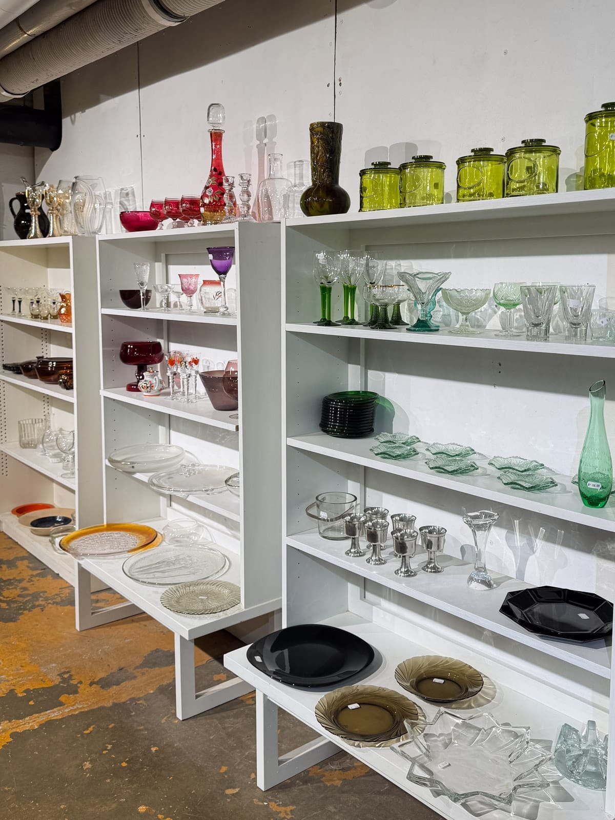 Shelves of vintage glassware and Finnish design pieces displayed at Fasaani Antiikki second-hand shop. 