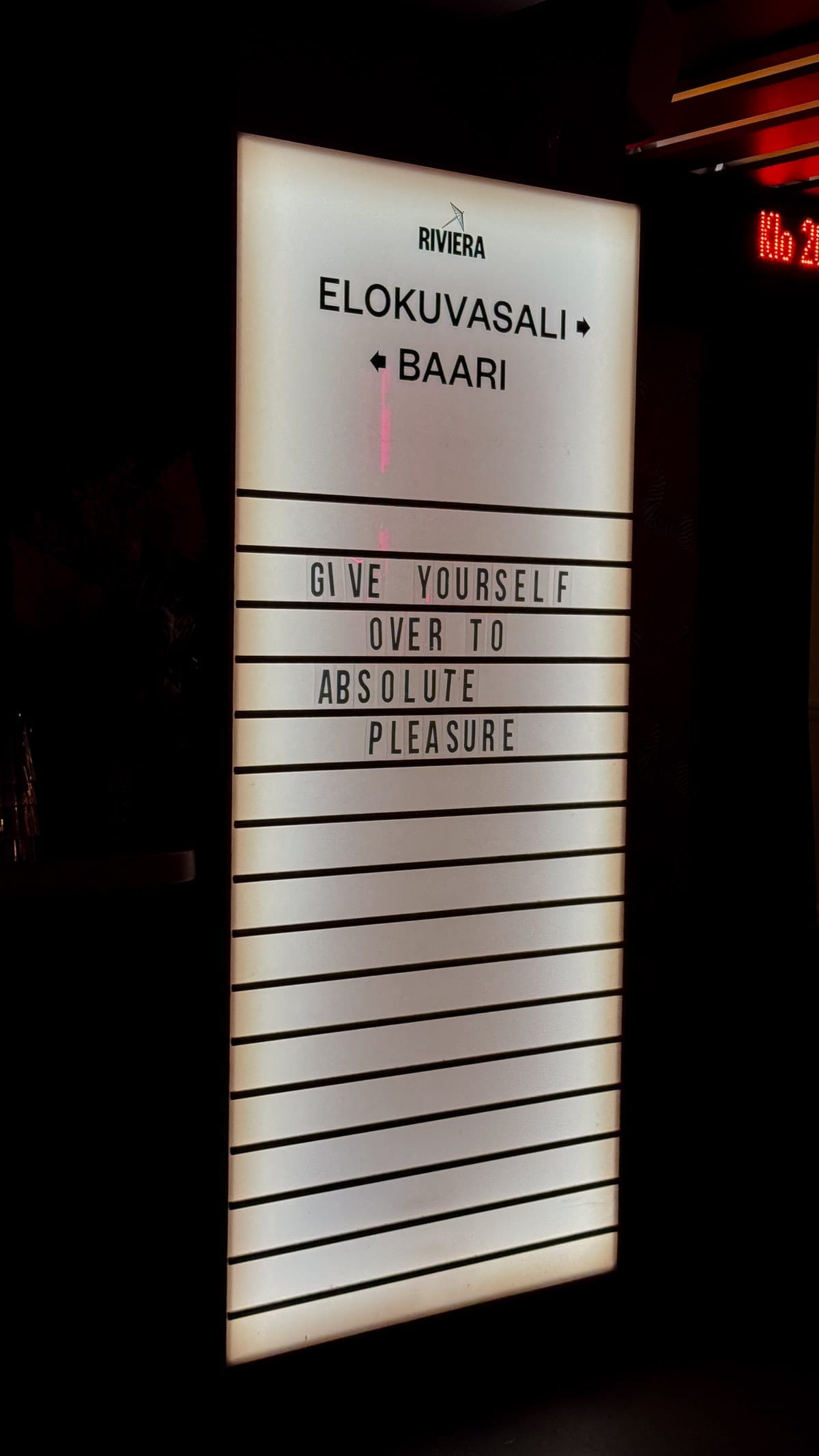 Illuminated Riviera Cinema sign in Helsinki reading “Give Yourself Over to Absolute Pleasure”