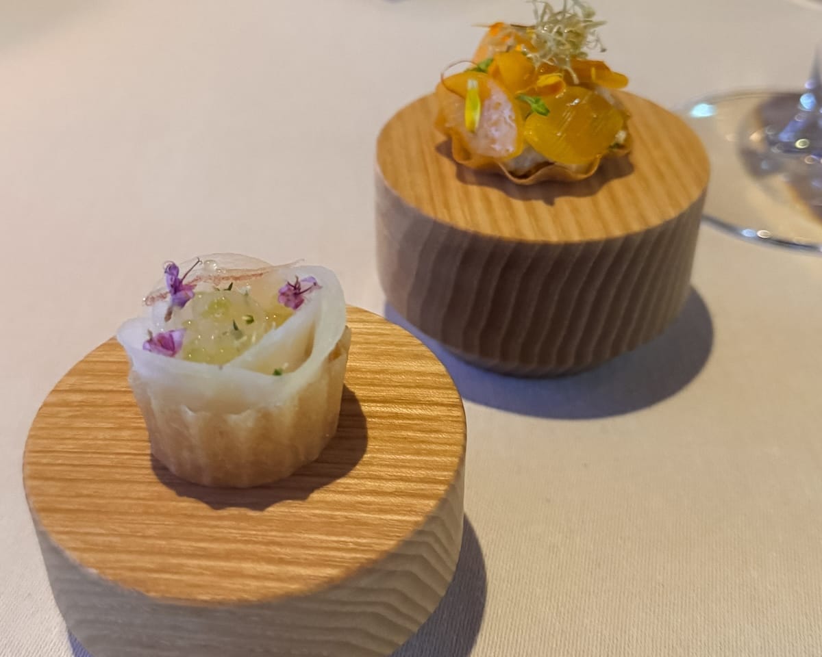 Modern Finnish tasting menu bites served on wooden pedestals at Palace Helsinki.