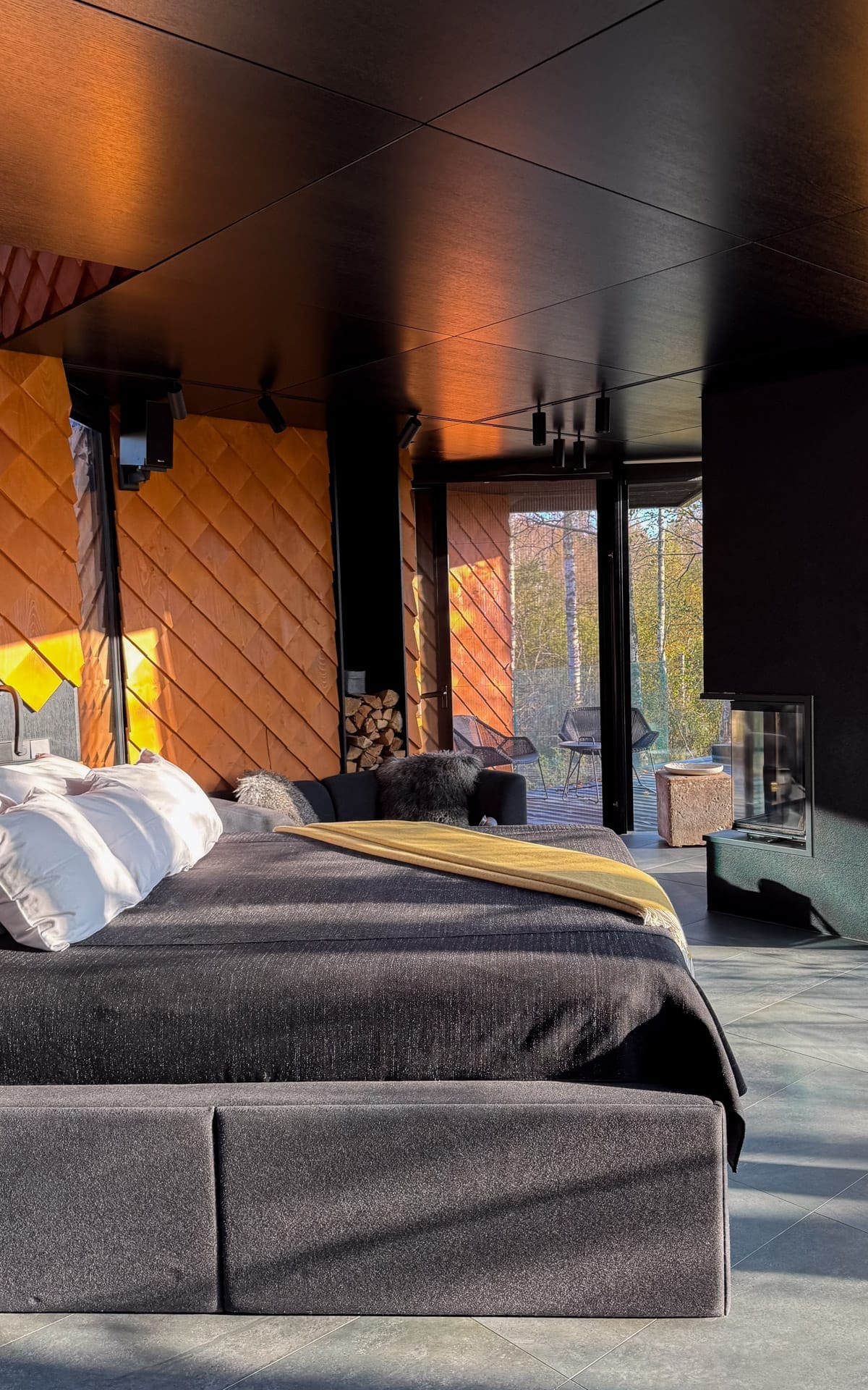 Modern bedroom of Kabi villa with fireplace, floor-to-ceiling windows and forest views at Maidla Nature Resort.