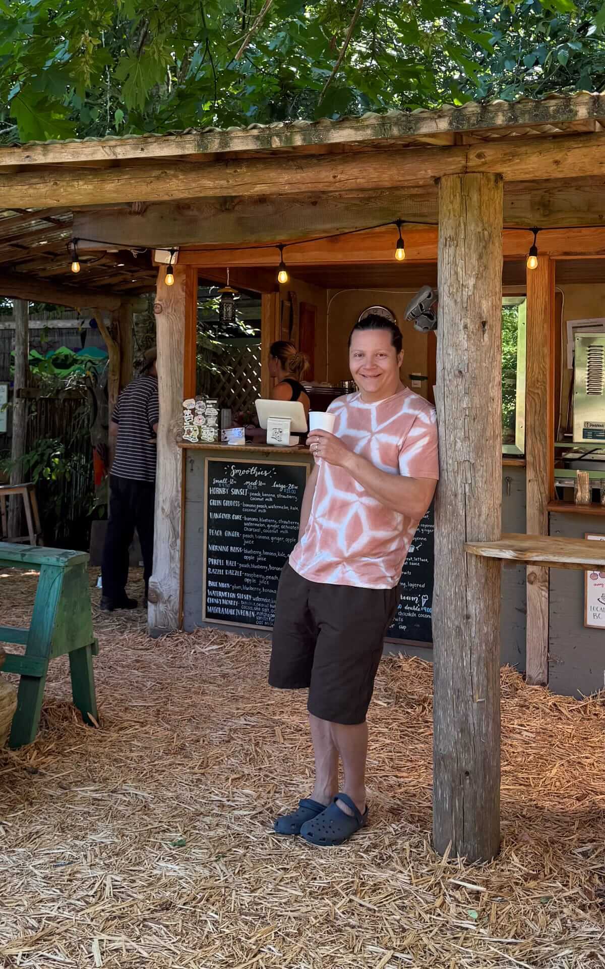 Ari enjoying his green juice from Hornby Island Juice Bar in the shaded outdoor seating area.
