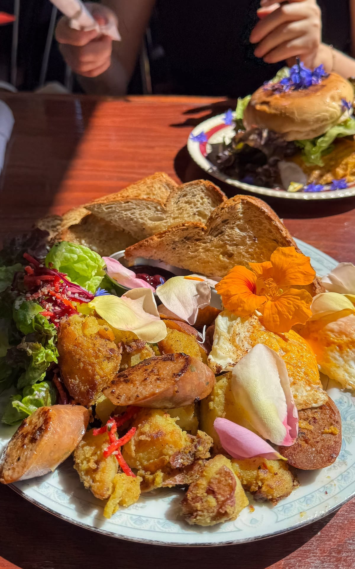 Colourful breakfast plate with potatoes, sausage, eggs, and edible flowers at Forage restaurant.