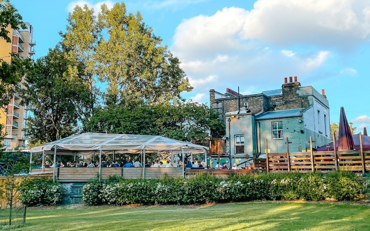 Outdoor pub garden in London with covered seating beside a park - perfect for a relaxing itinerary stop.