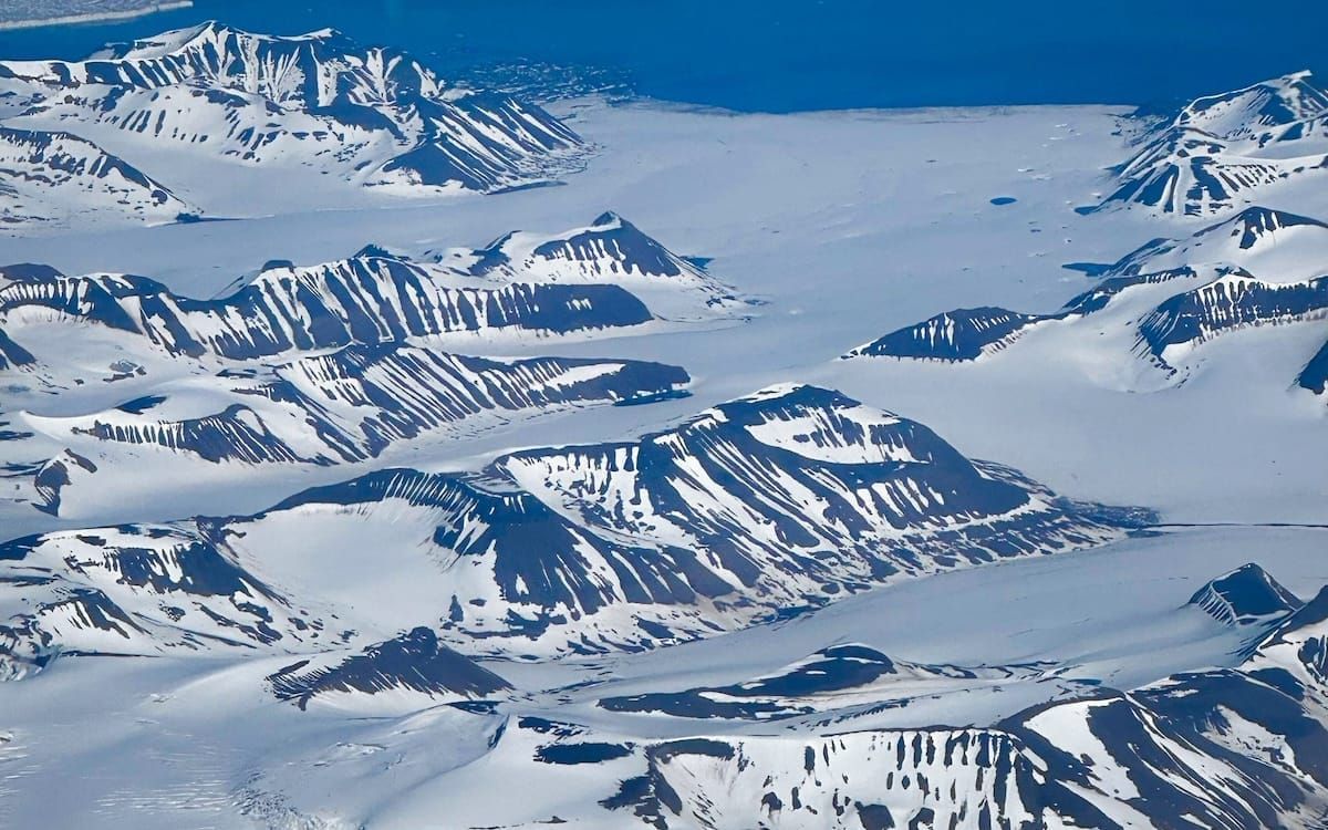 Aerial view of snow-covered mountains and vast glaciers in Svalbard, an incredible travel destination in the Arctic.