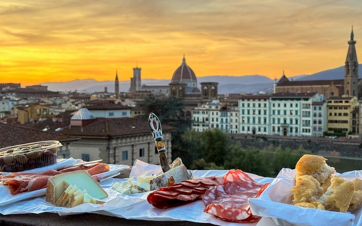 A sunset picnic of Italian cheeses and charcuterie overlooking the romantic city skyline of Florence, one of Europe's unforgettable travel destinations.