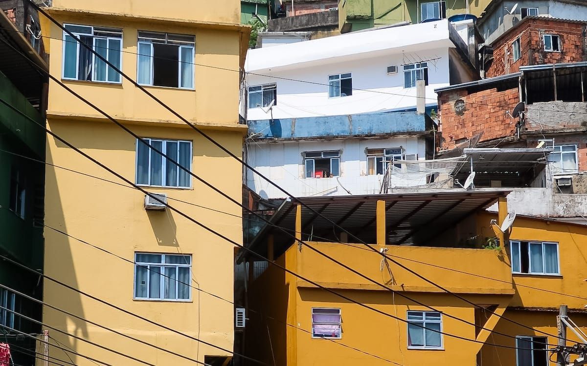 Tall, closely packed buildings painted in bold colours, connected by a web of visible wiring in Rocinha, one of Rio’s largest favelas that you don't want to miss seeing on a walking tour.