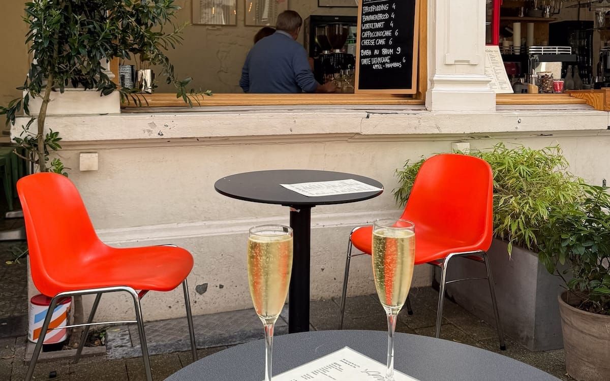 Two glasses of sparkling wine on an outdoor table at Antoine cafe-bar, one of the unique things to do in Antwerp for a stylish aperitif.