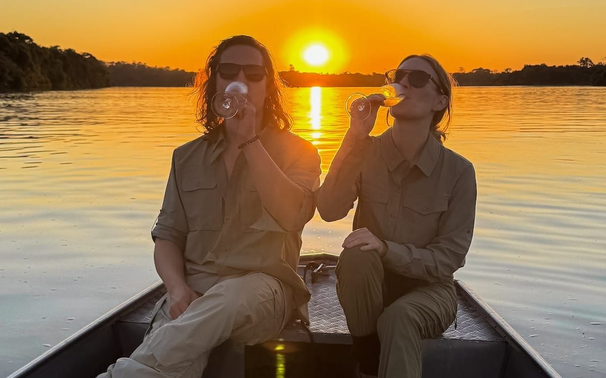 Cec and Ari drinking champagne on a small boat during sunset on the Amazon River, a stop on the Brazil and Argentina itinerary.