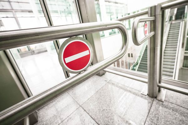 Metal gates with a no entry sign in a building lobby.