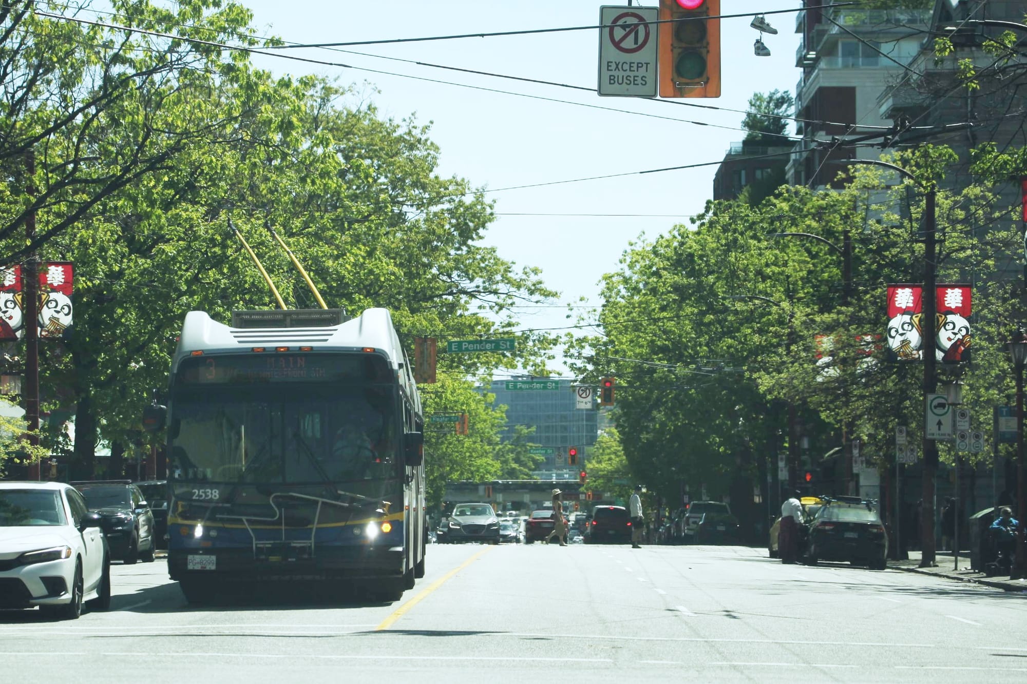 A bus is stopped below a sign that says no left turns except buses