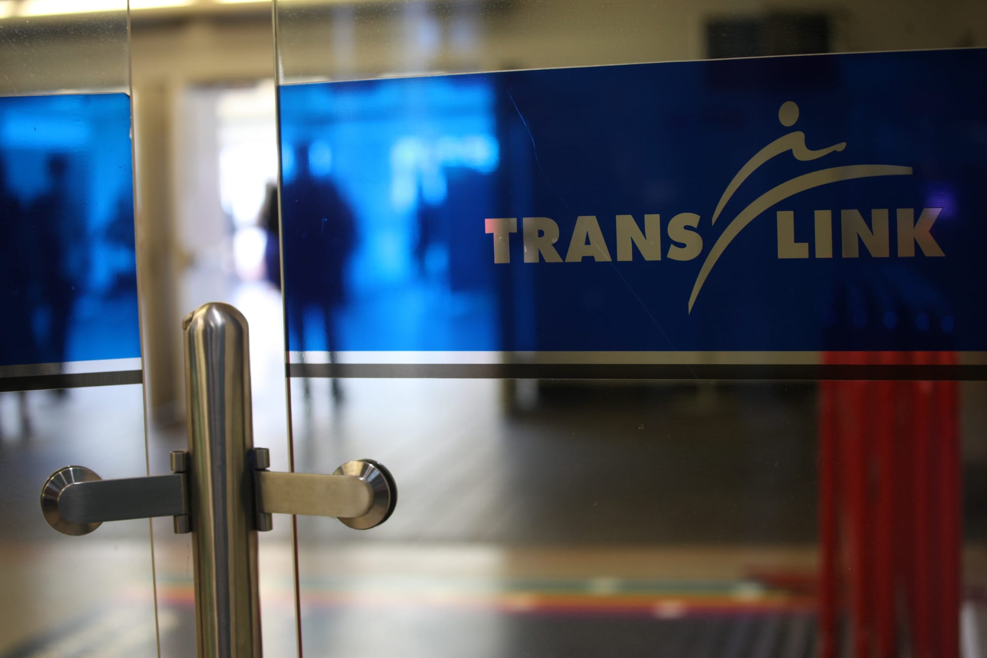 A TransLink logo adorns a transparent glass with a silhouetted figure standing in the background