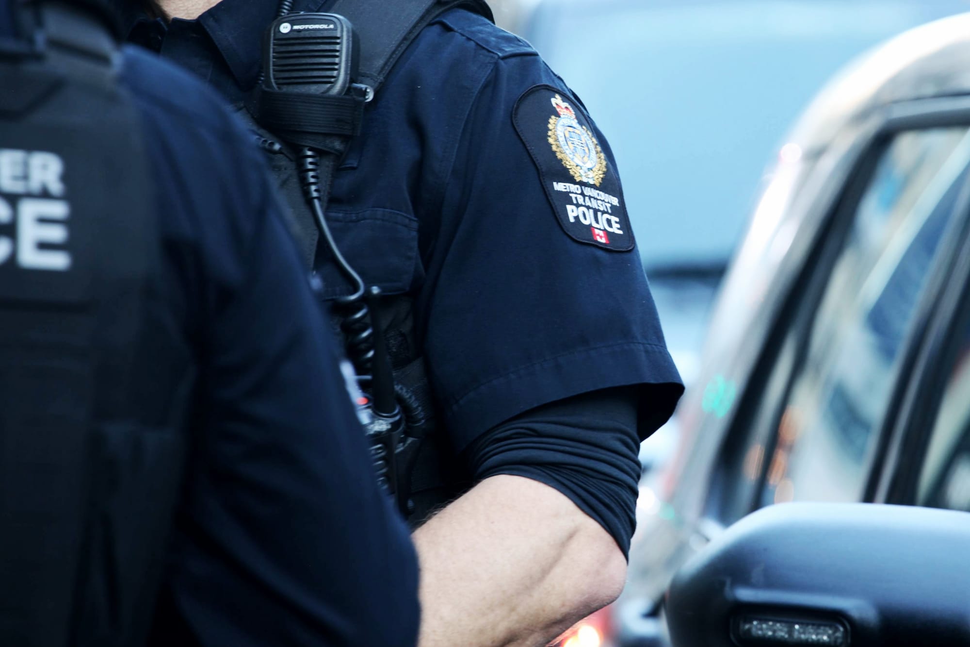 Two police officers' badges are seen beside a police car