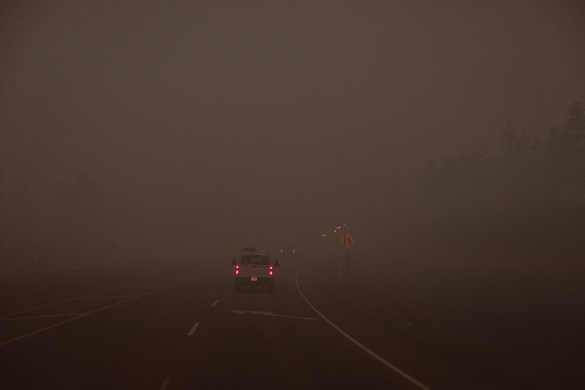 The convoy is barely visible in the dark grey smoke blanketing the road