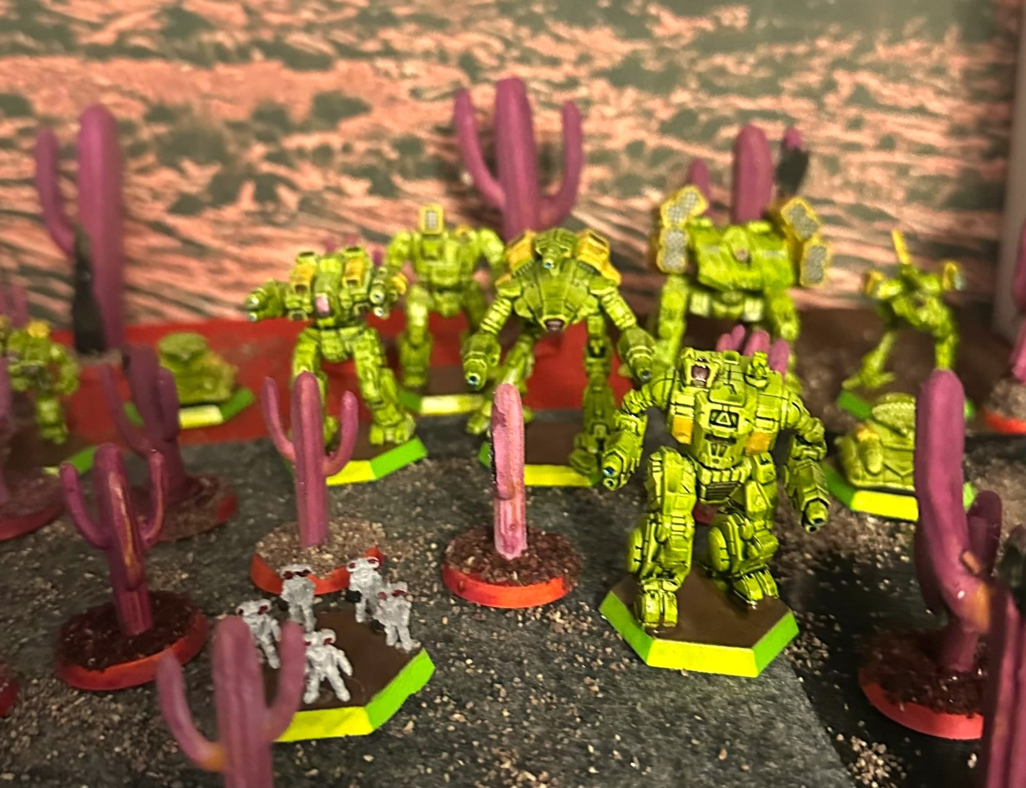 Flocked felt ground in black, gray, brown and red, with purple "alien" cacti with some "black mold" and a variety of Battlemechs, sci-fi tanks, and sci-fi infantry in a green and yellow paint scheme. 