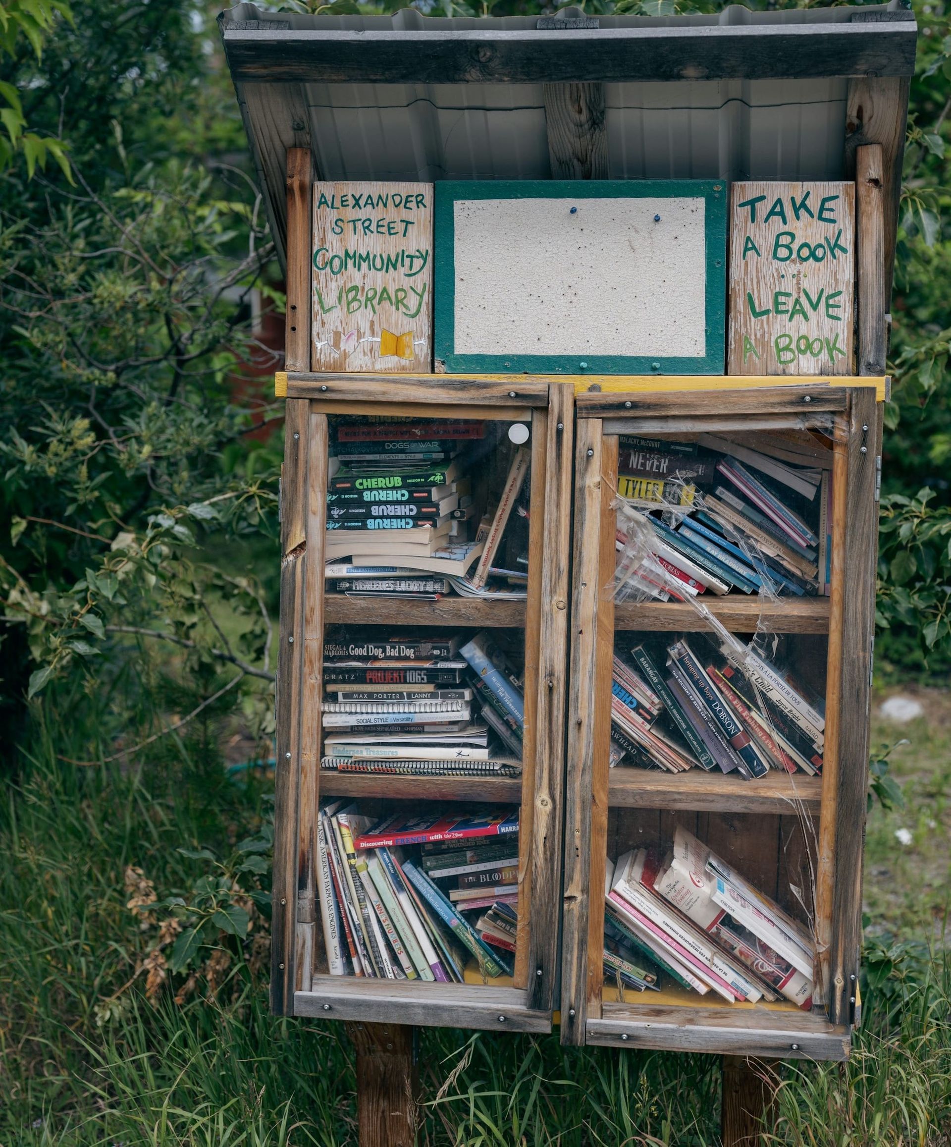 a wooden bookcase outside full of books for the neighborhood community to share