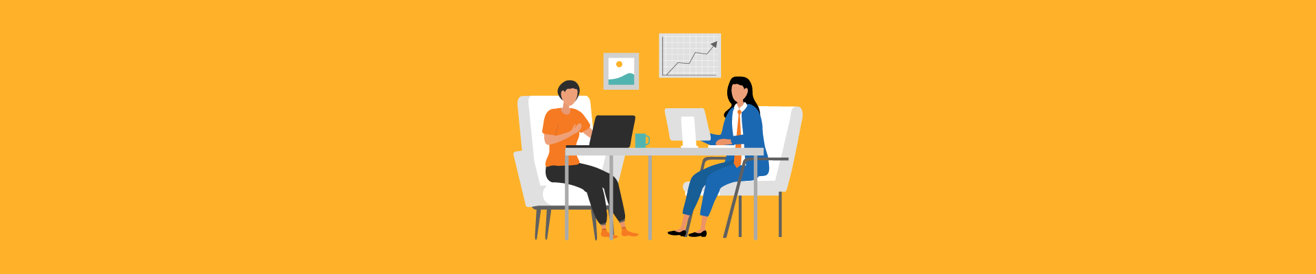 Two women sitting across a desk working on laptops with charts on the wall behind them.