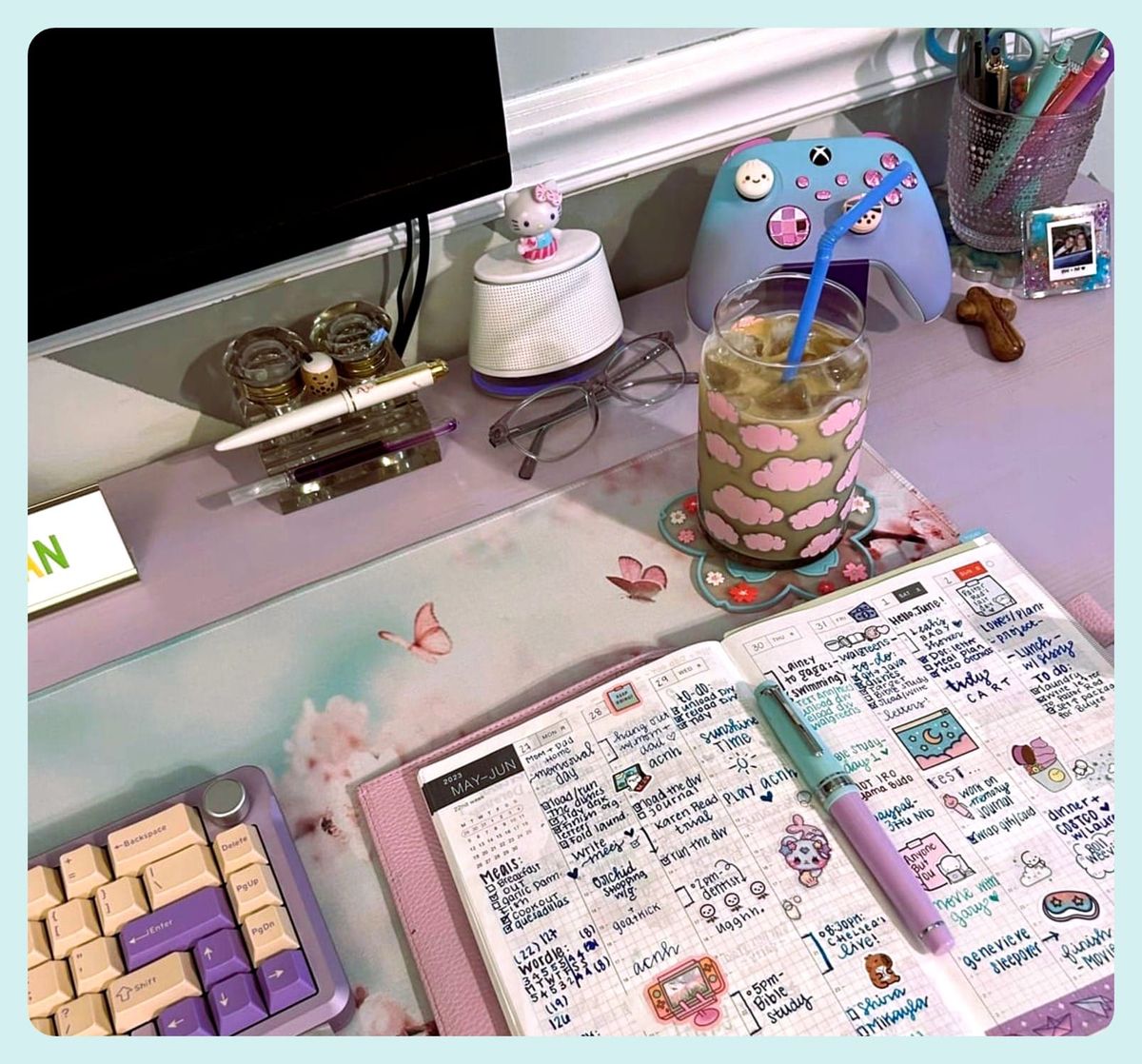 Photo of a desk showing various pastel-colored items, including an open planner with a pen on top.