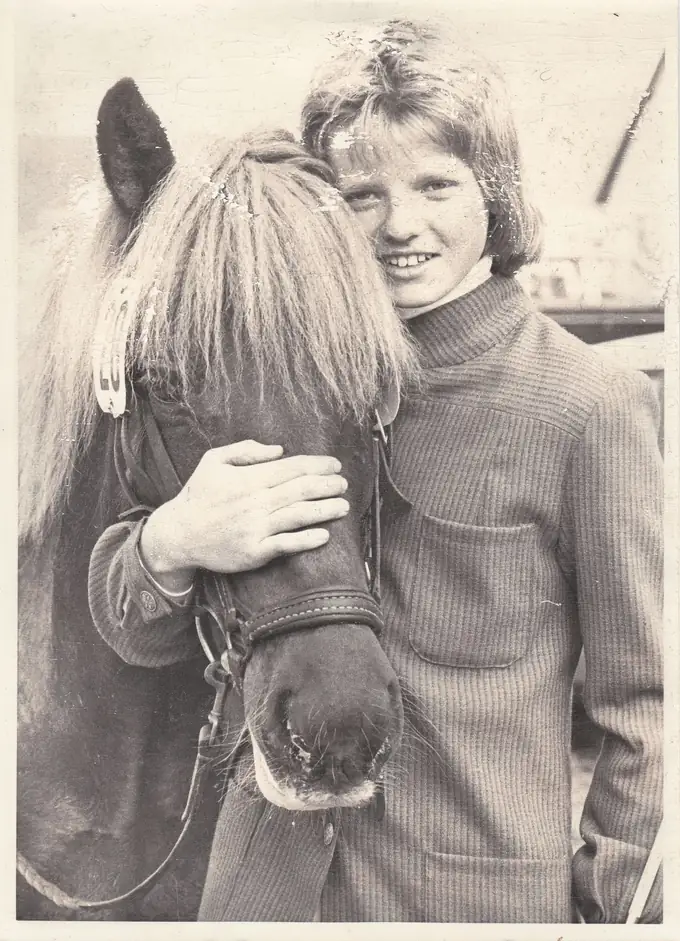 A boy resting his head against an Icelandic horse's neck, one hand on the horse's nose. Black and white, 1977.