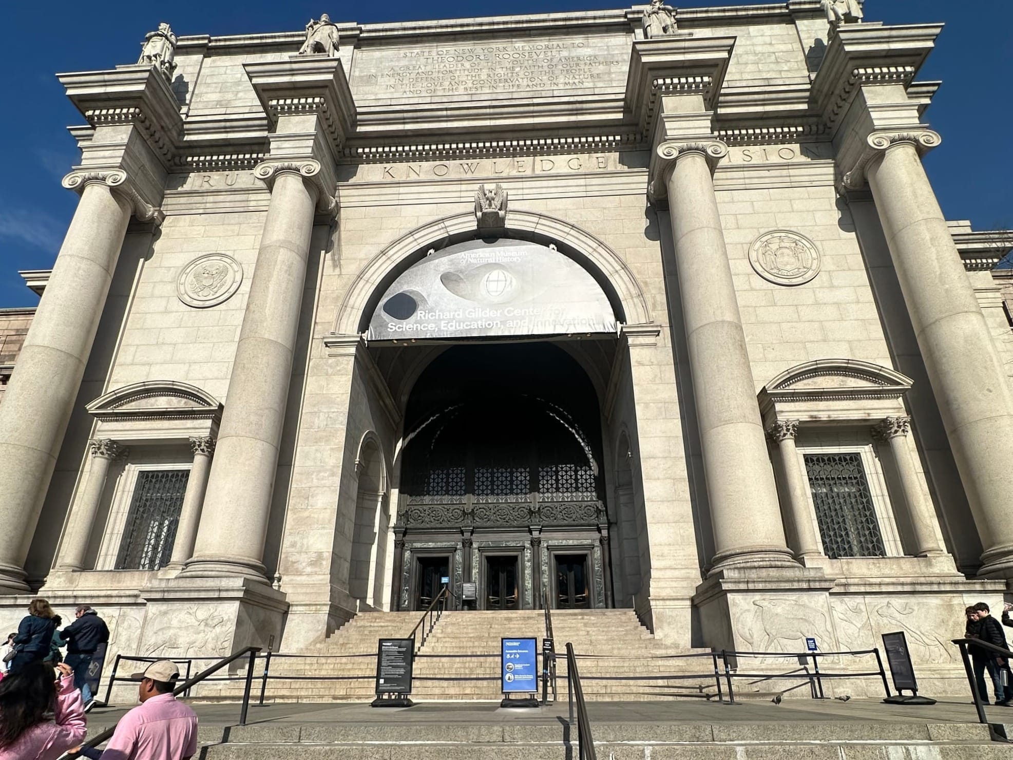 A family on the steps of the American Museum of Natural History on a sunny day, a stop on this family trips NYC itinerary