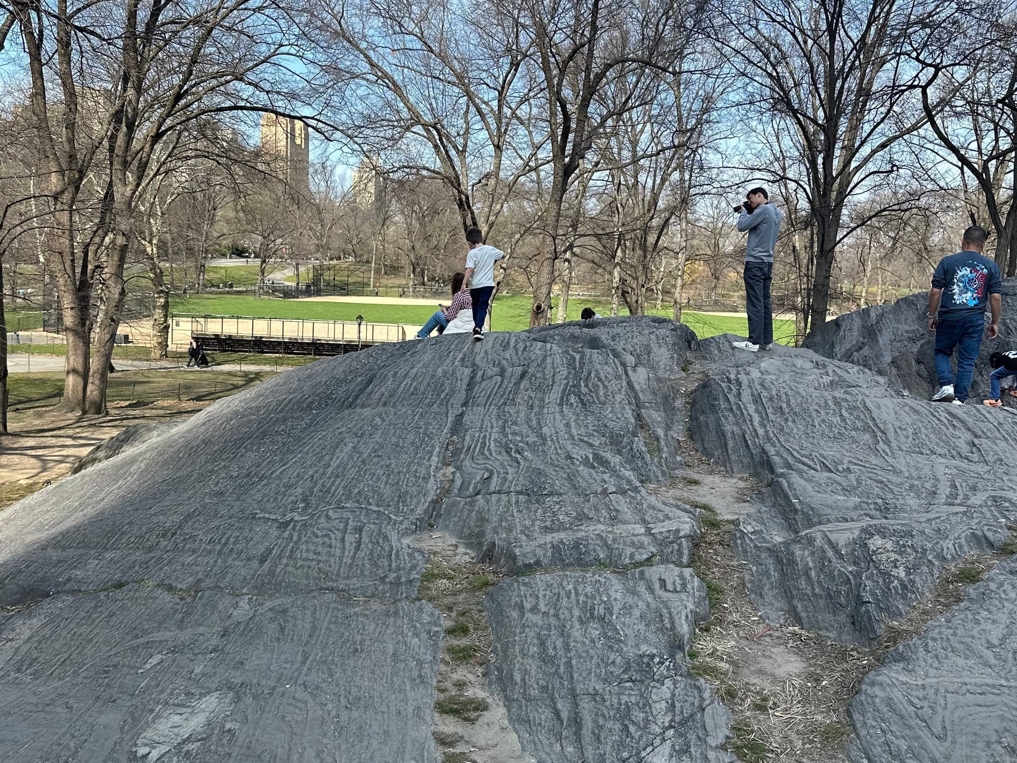 A kid playing on the boulders in Central Park in the area around Heckscher Playground 