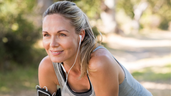 A woman taking a break from exercising outdoors, smiling and looking energized.