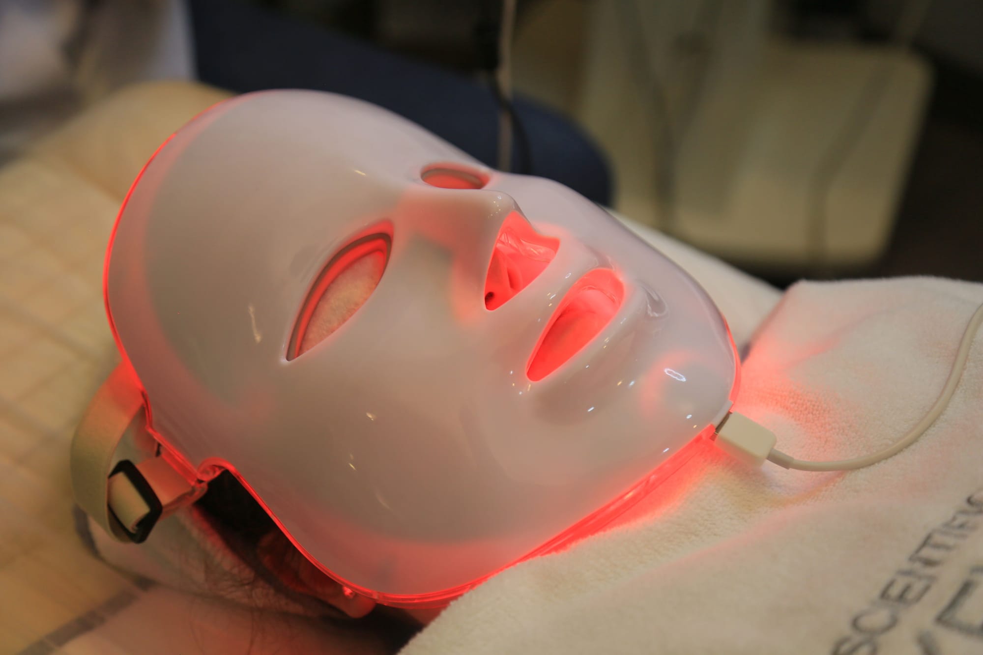 Person lying down wearing a red LED light therapy face mask.